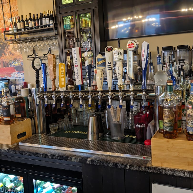 A well-stocked bar at Portofino's, featuring beer taps, liquor bottles, and wine on shelves.