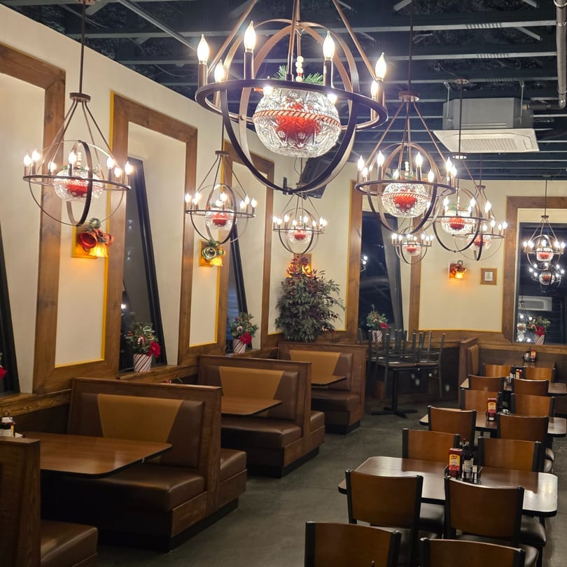 Portofino's dining room with booths, tables, and ornate chandeliers decorated for Christmas.